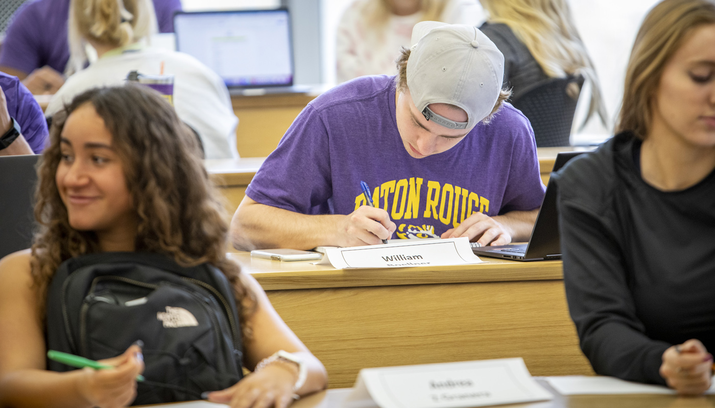 student writing at desk in classroom