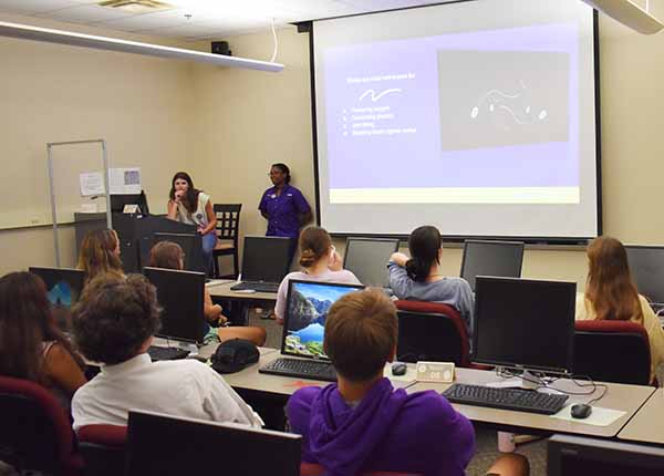 A classroom of students looks at a projector screen