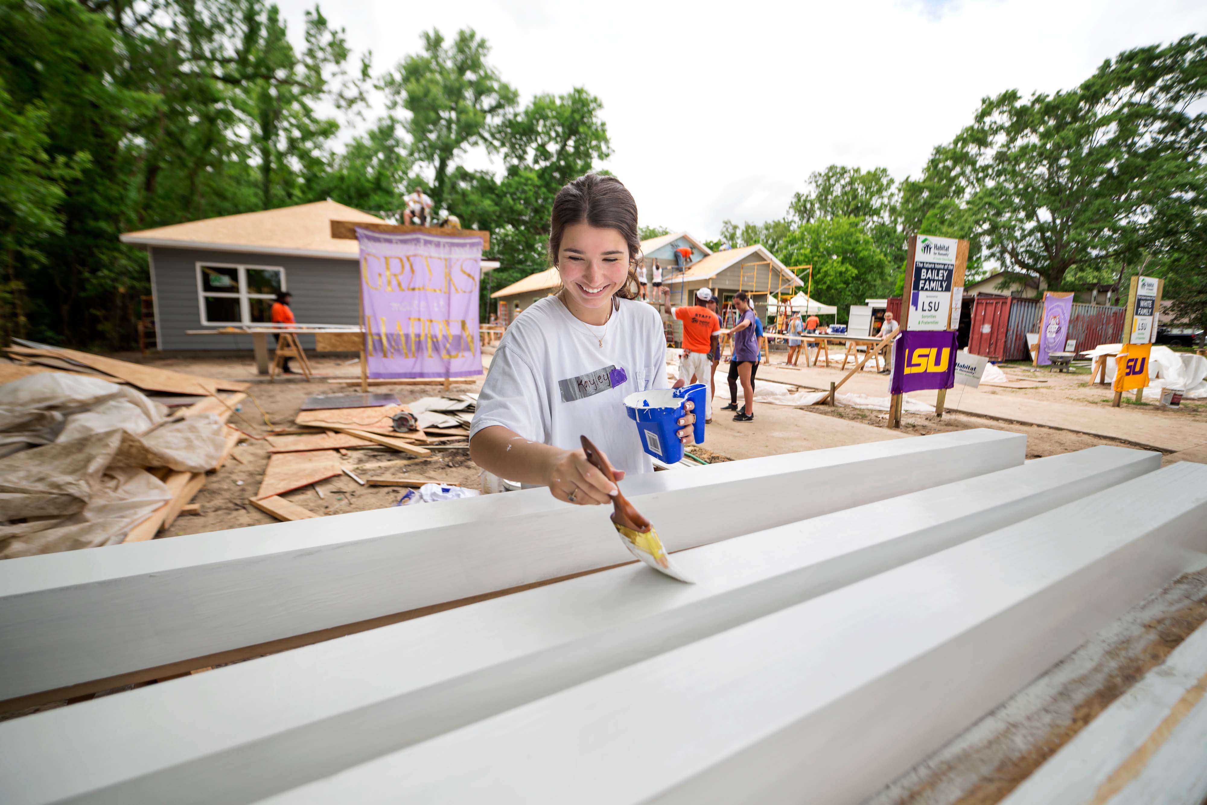 sorority member painting a house